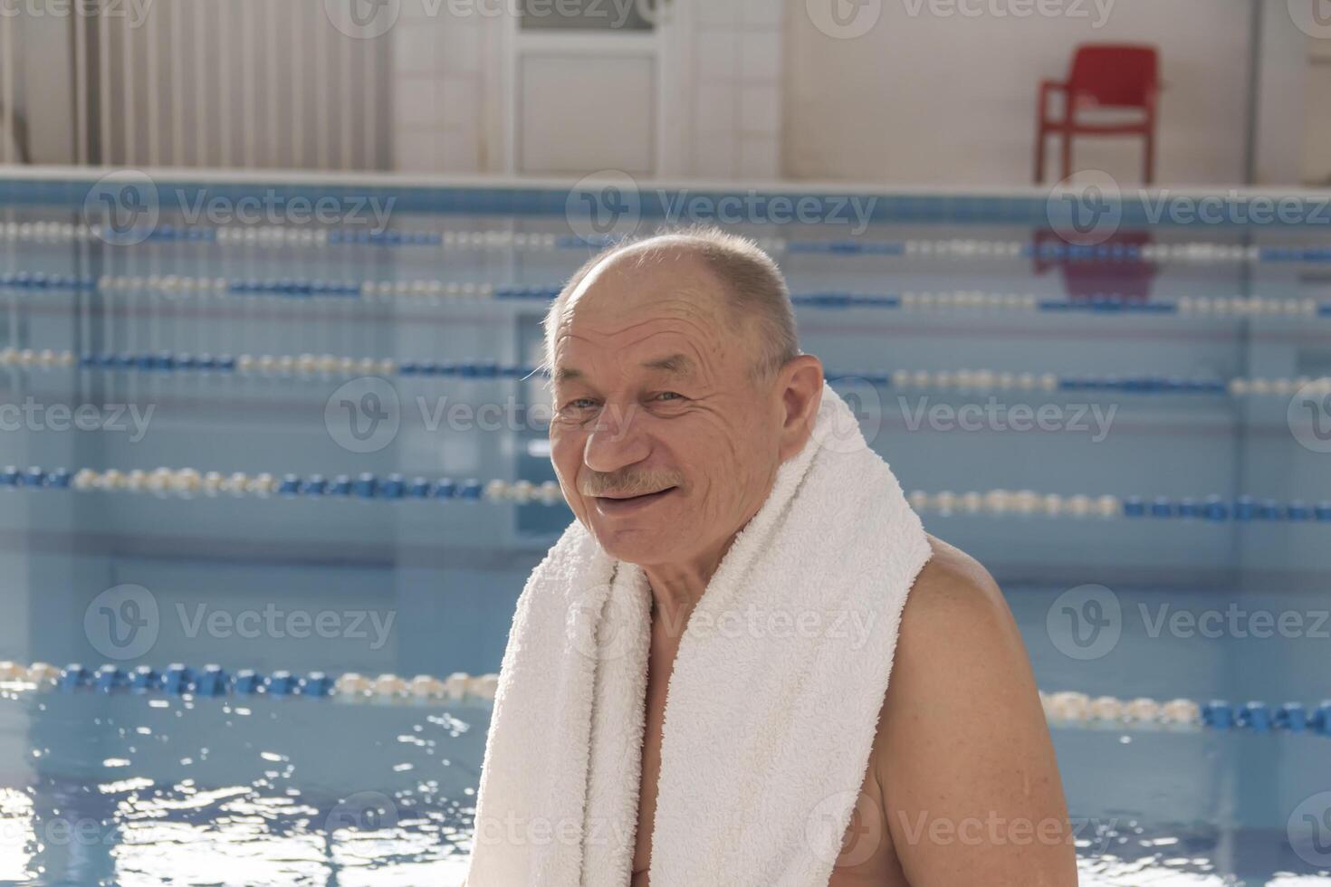 A 70-year-old man, grandfather pensioner is resting, swimming, recovering in the pool with clear and blue water in the hotel. photo