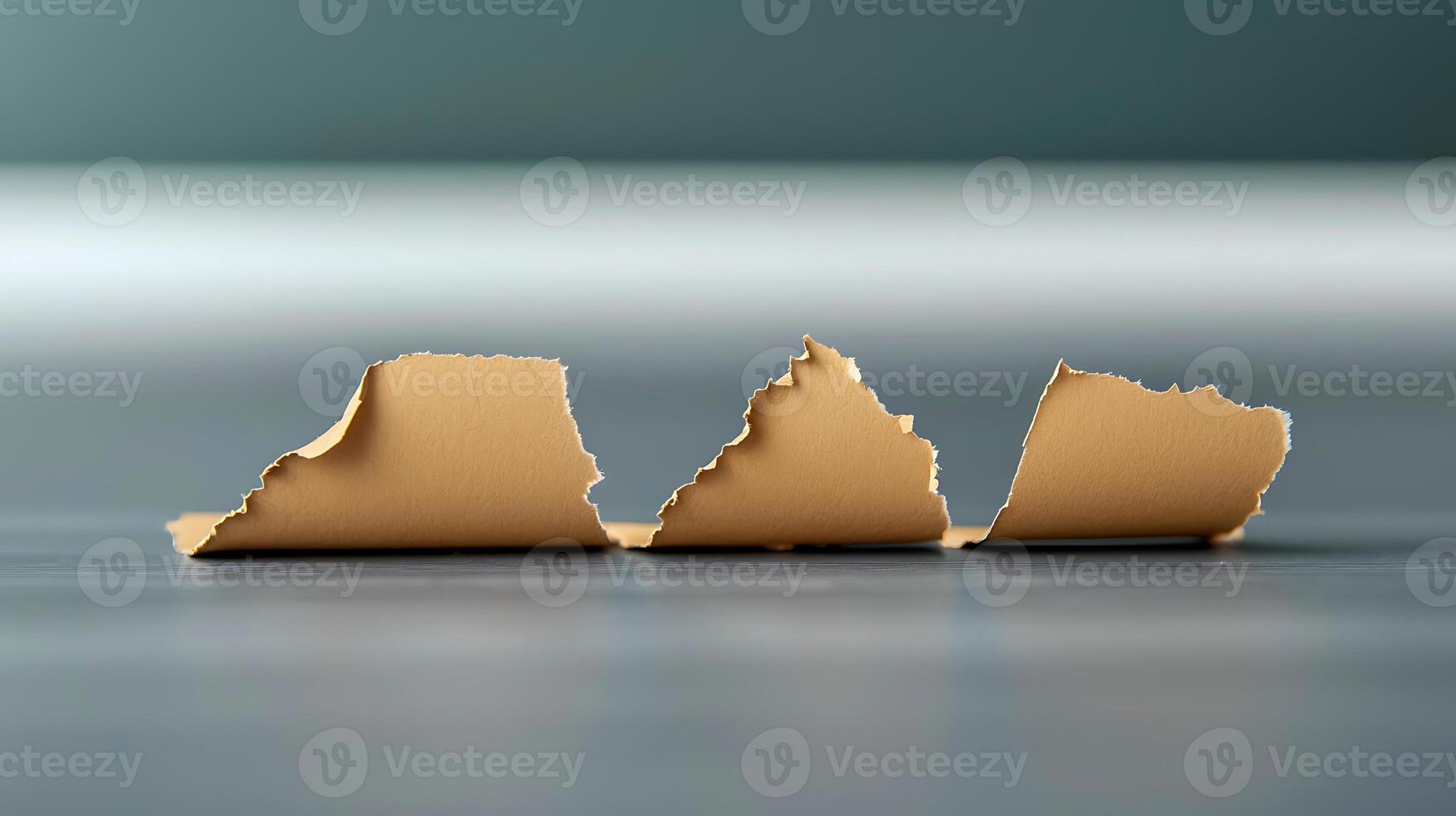 Close-up of three torn pieces of textured paper on a smooth surface with a blurred background photo