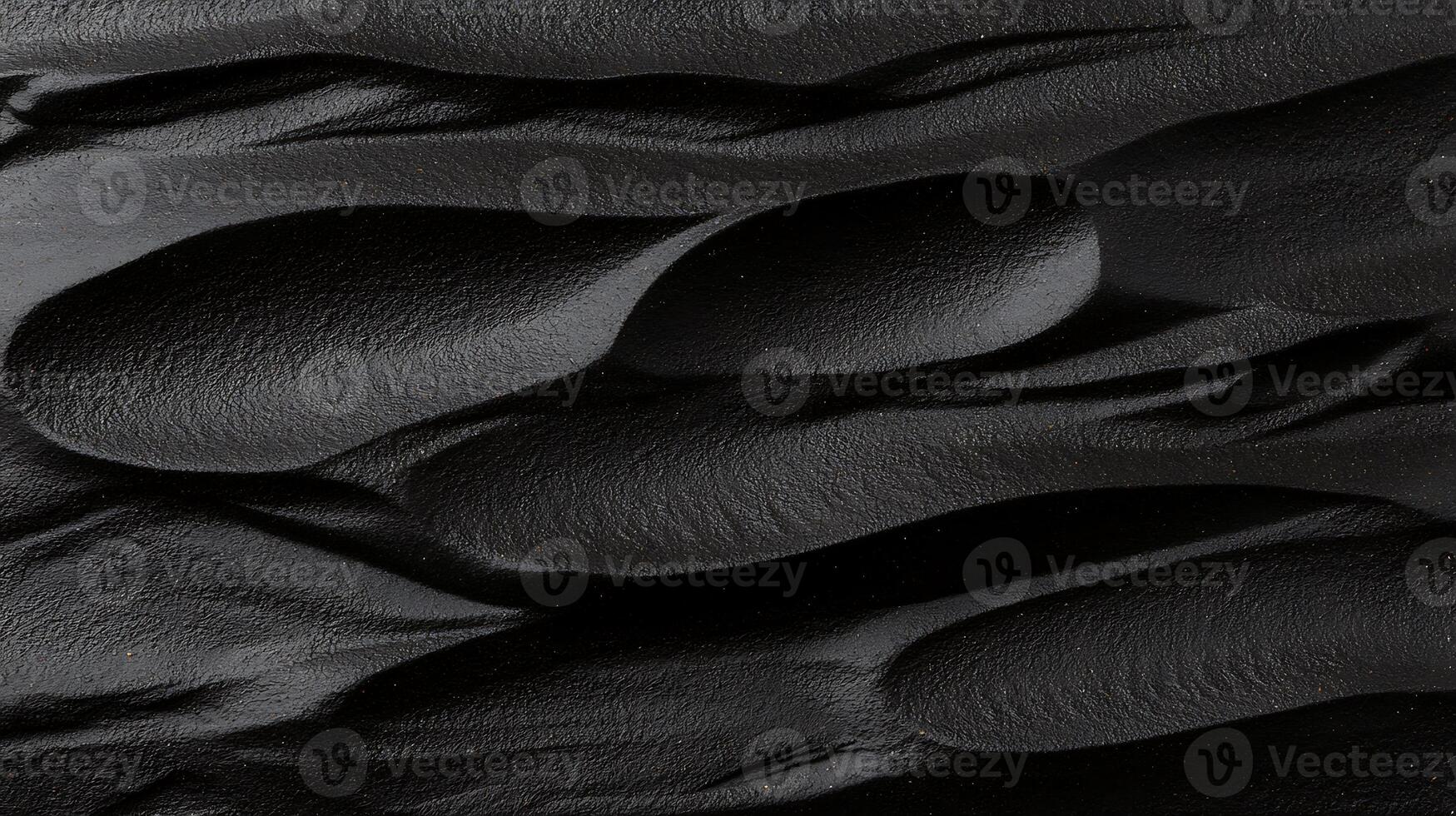 Close-up of textured black surface with flowing patterns resembling natural formations photo