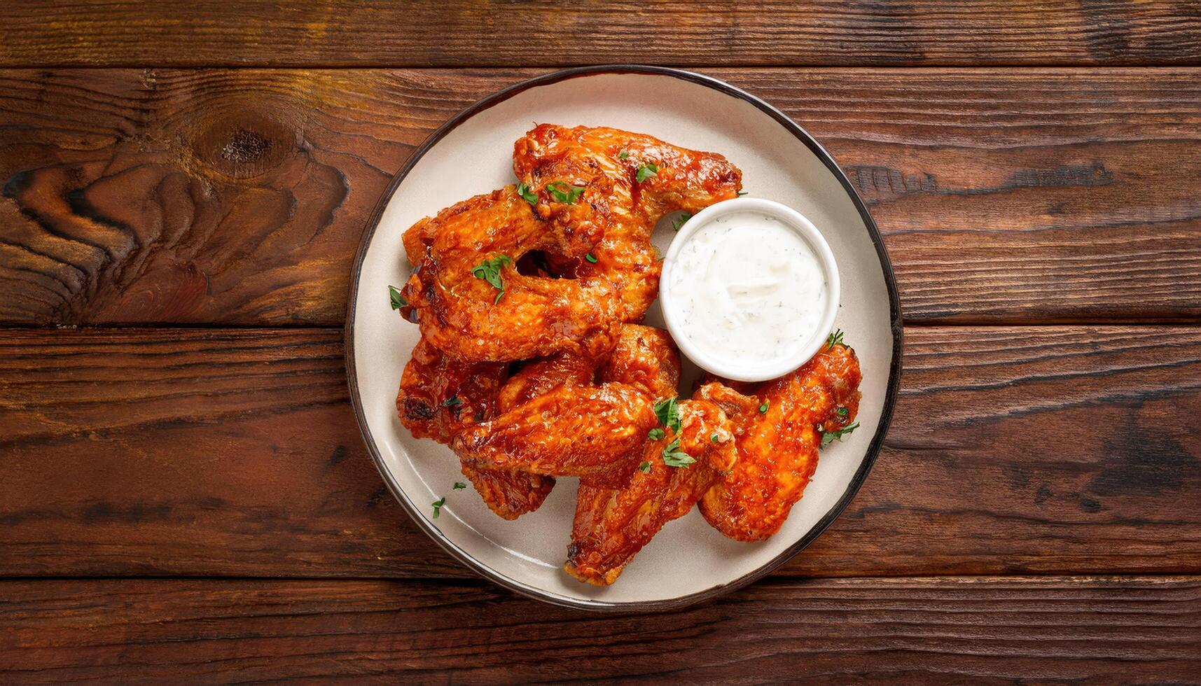 Grilled chicken wings marinated in a spicy buffalo sauce on wooden table top view photo