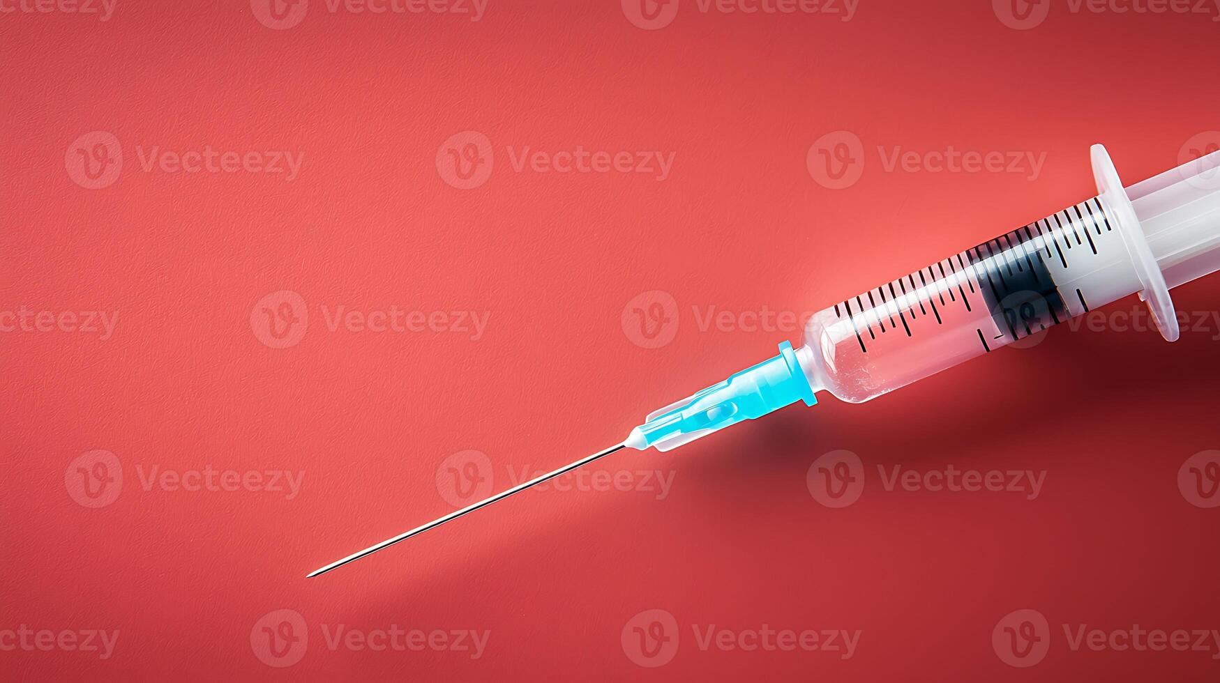 Close-up of a syringe with a clear needle on a vibrant red background, emphasizing medical use photo