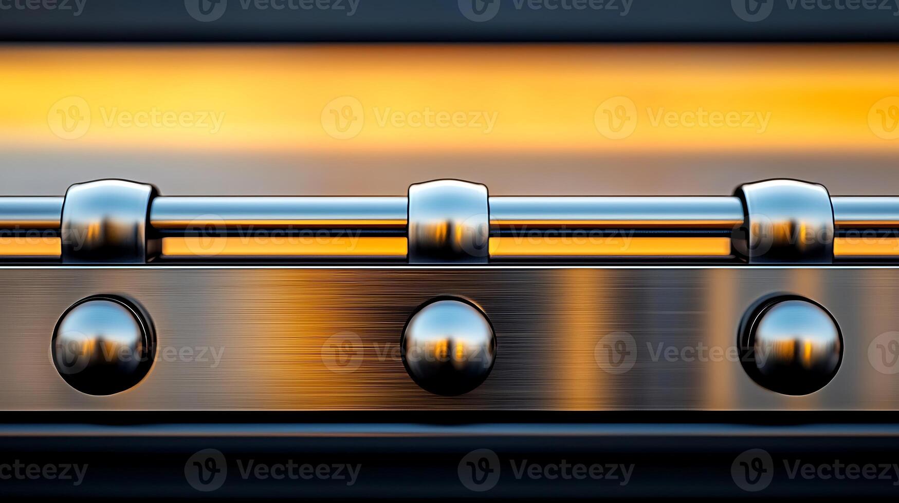 Close-up of a metallic hinge reflecting warm light against a blurred background, showcasing detail photo