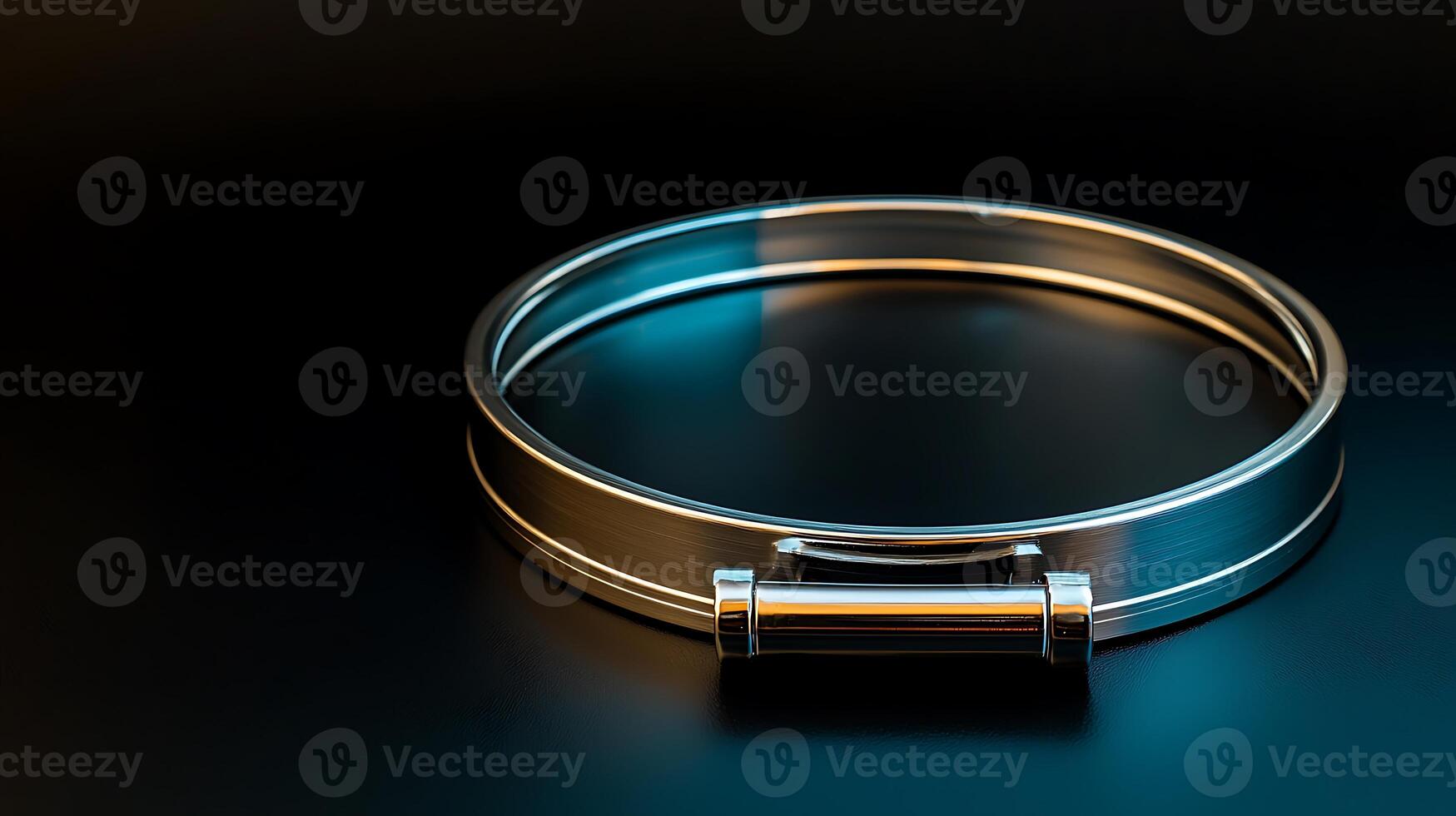 Sleek metallic bracelet resting on a dark surface, illuminated by soft blue and silver light photo
