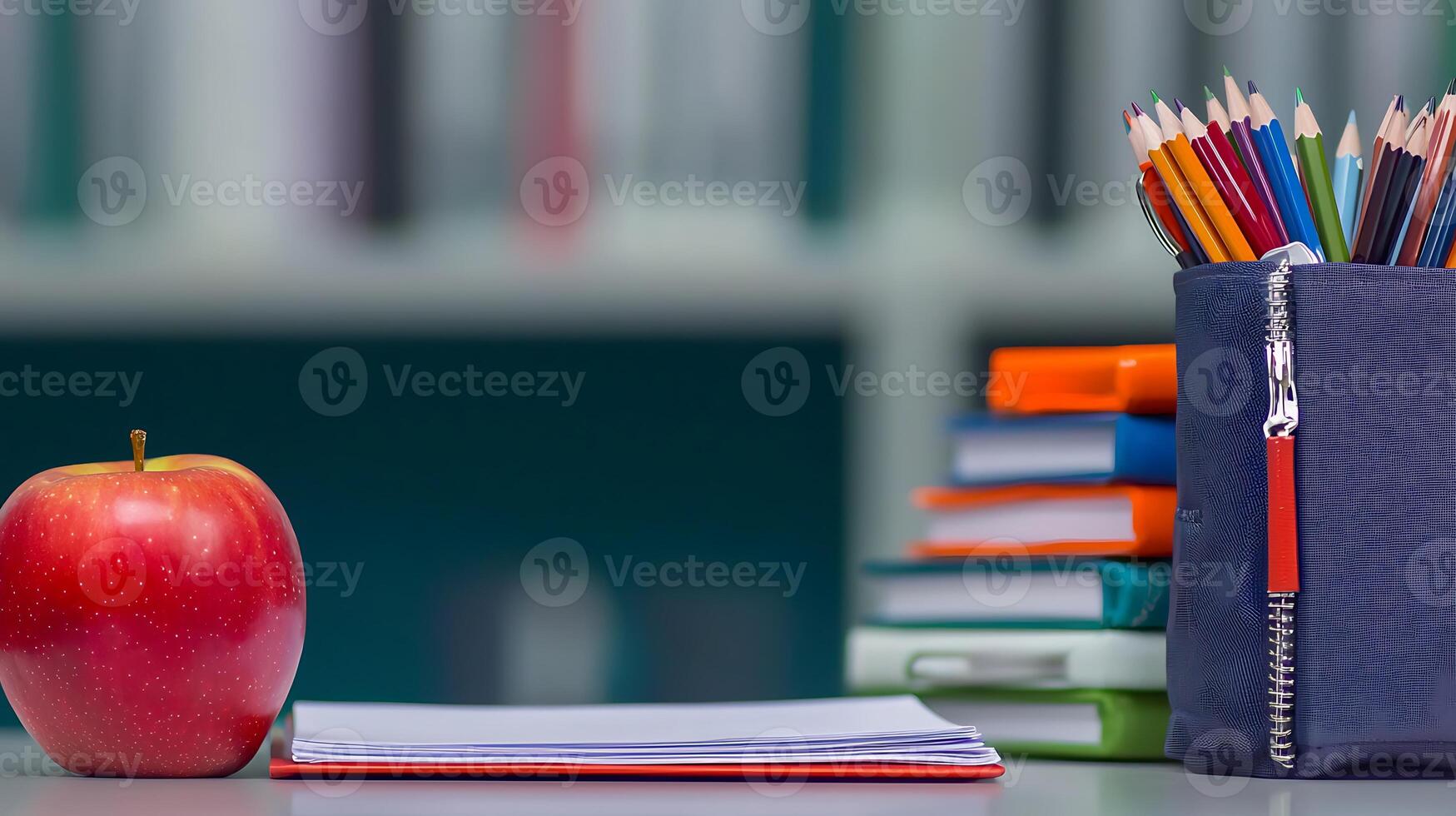 A vibrant red apple next to a stack of colorful notebooks and pencils in a study area photo