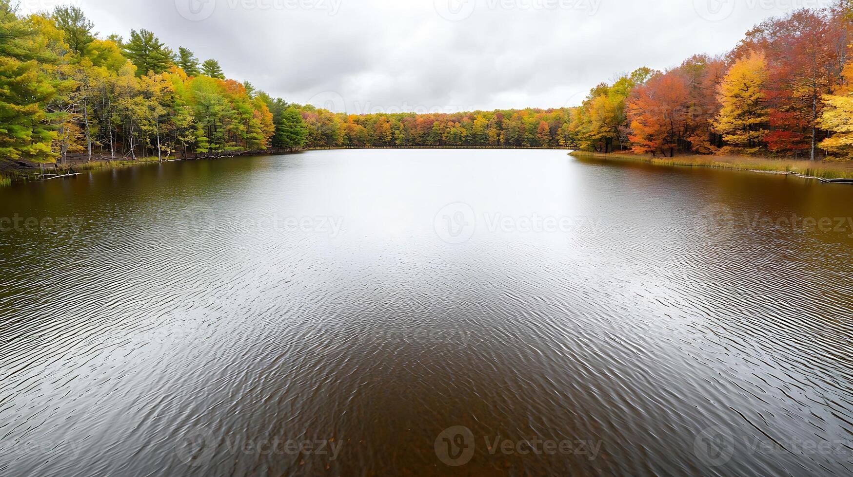 Tranquil autumn lake scene reflecting colorful foliage under a cloudy sky photo