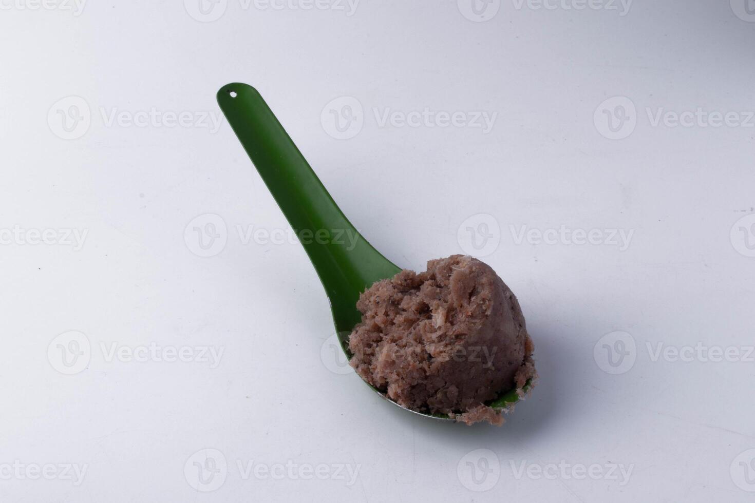 green spoon holds scoop of brown ice cream against plain background, highlighting its creamy texture photo