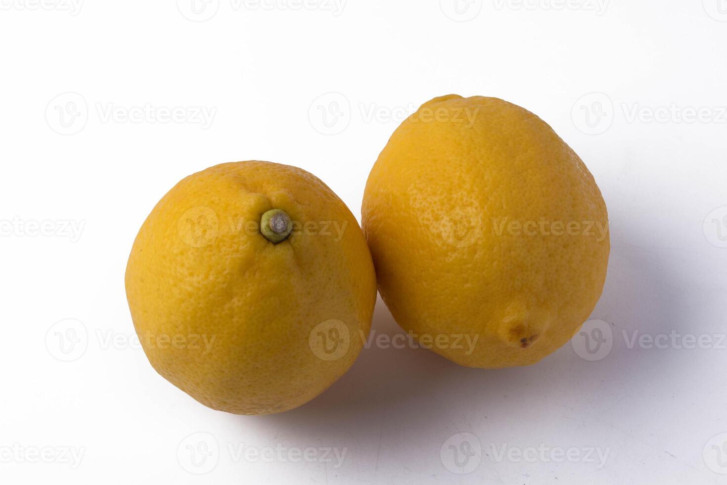 Two fresh lemons on white background, showcasing their vibrant yellow color and textured skin photo