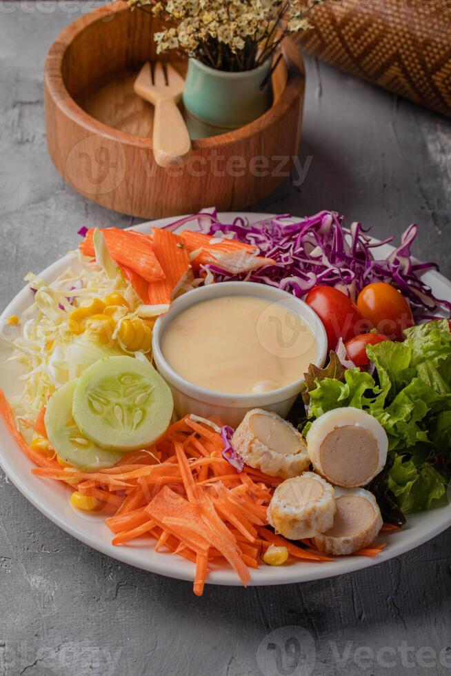 vibrant salad plate featuring fresh vegetables like carrots, cucumbers, cherry tomatoes, and cabbage, accompanied by creamy dressing in center, offers healthy and colorful meal option photo