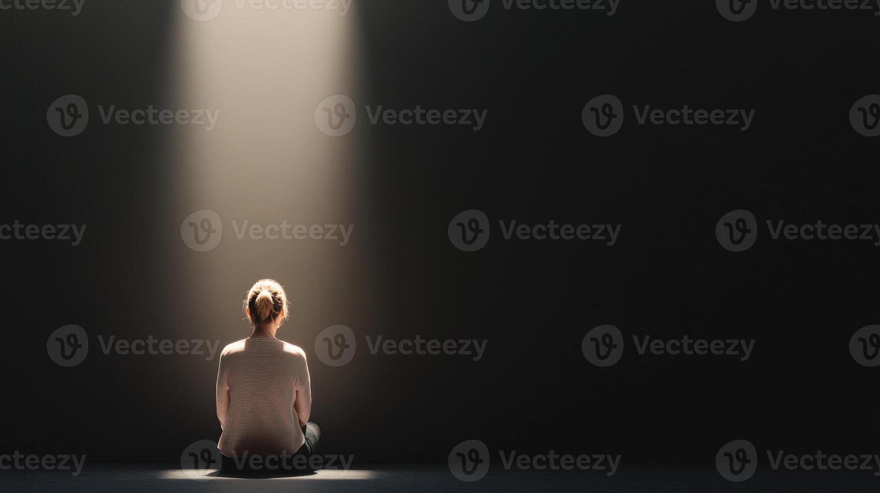 woman sits alone in dark room, illuminated by single beam of light, creating contemplative and introspective atmosphere photo