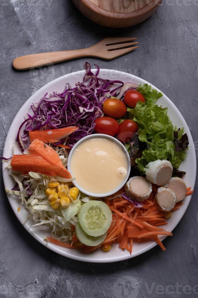 vibrant salad plate with fresh vegetables including shredded cabbage, cherry tomatoes, lettuce, sliced carrots, corn, cucumber, and sliced boiled eggs, centered around creamy dressing photo