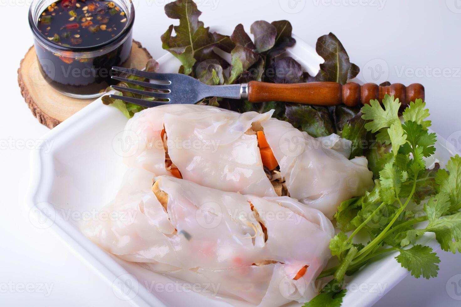 Fresh Vietnamese spring rolls with vegetables and herbs served with side of soy dipping sauce on white plate. presentation includes fork and garnished with cilantro and lettuce photo