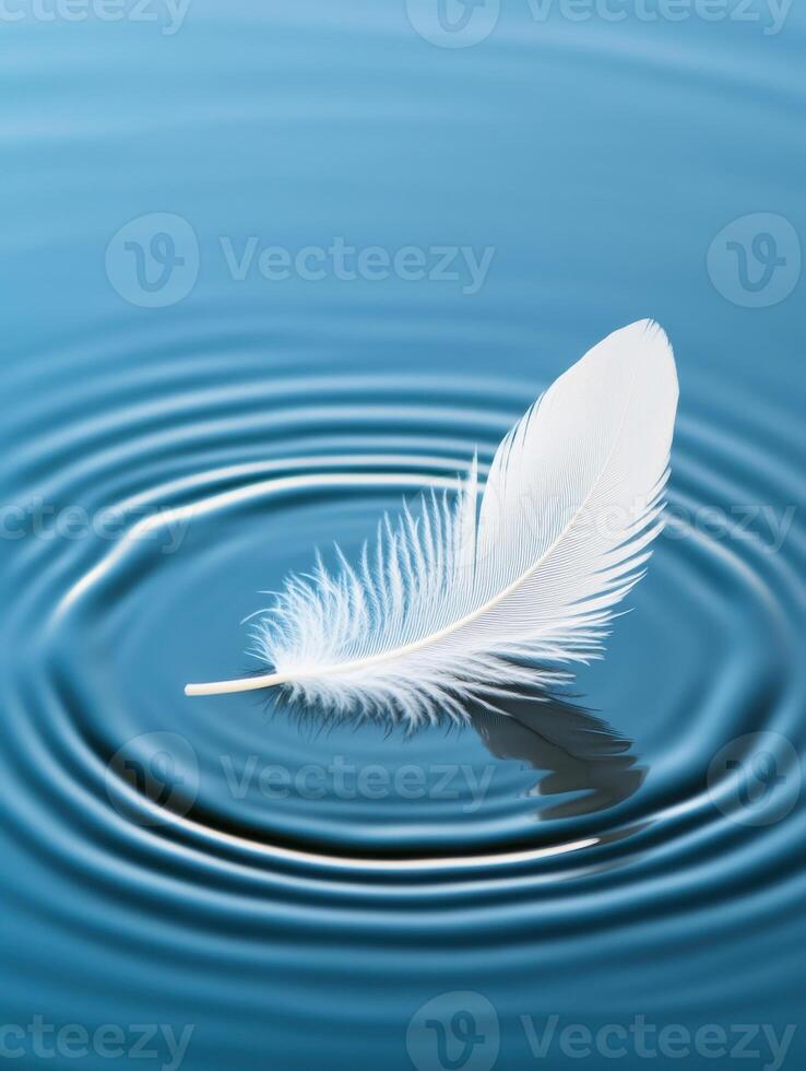 Delicate white feather floating on calm water, creating gentle ripples photo