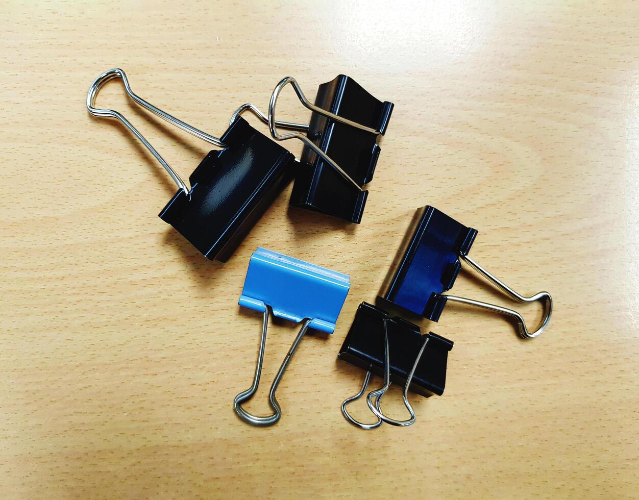 Many black and blue paper clips on wooden table with copy space. Office object on wood background concept photo