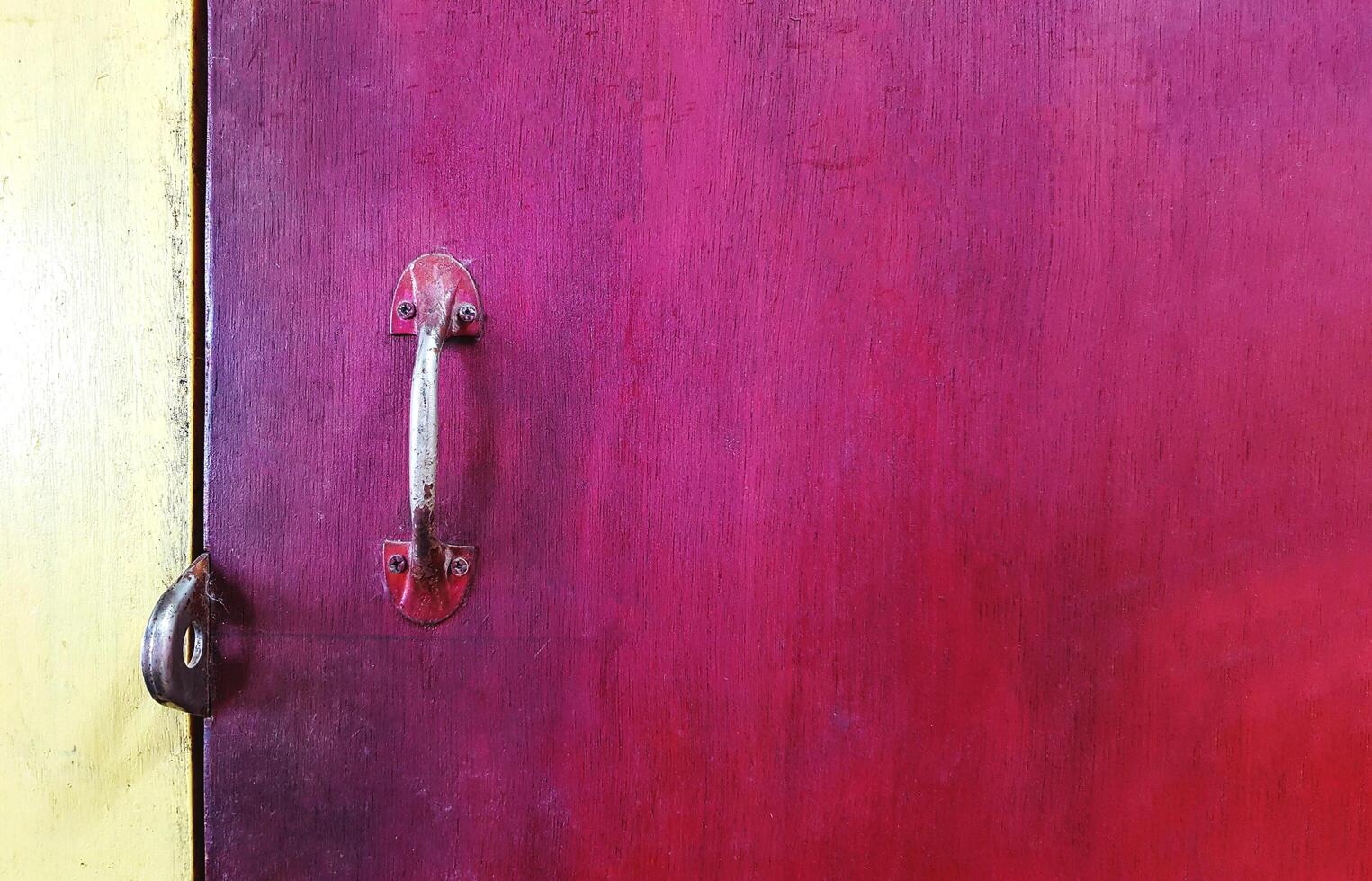 Close up metal handle of door or window on red wooden background painted with copy space. Art and Abstract wallpaper. photo