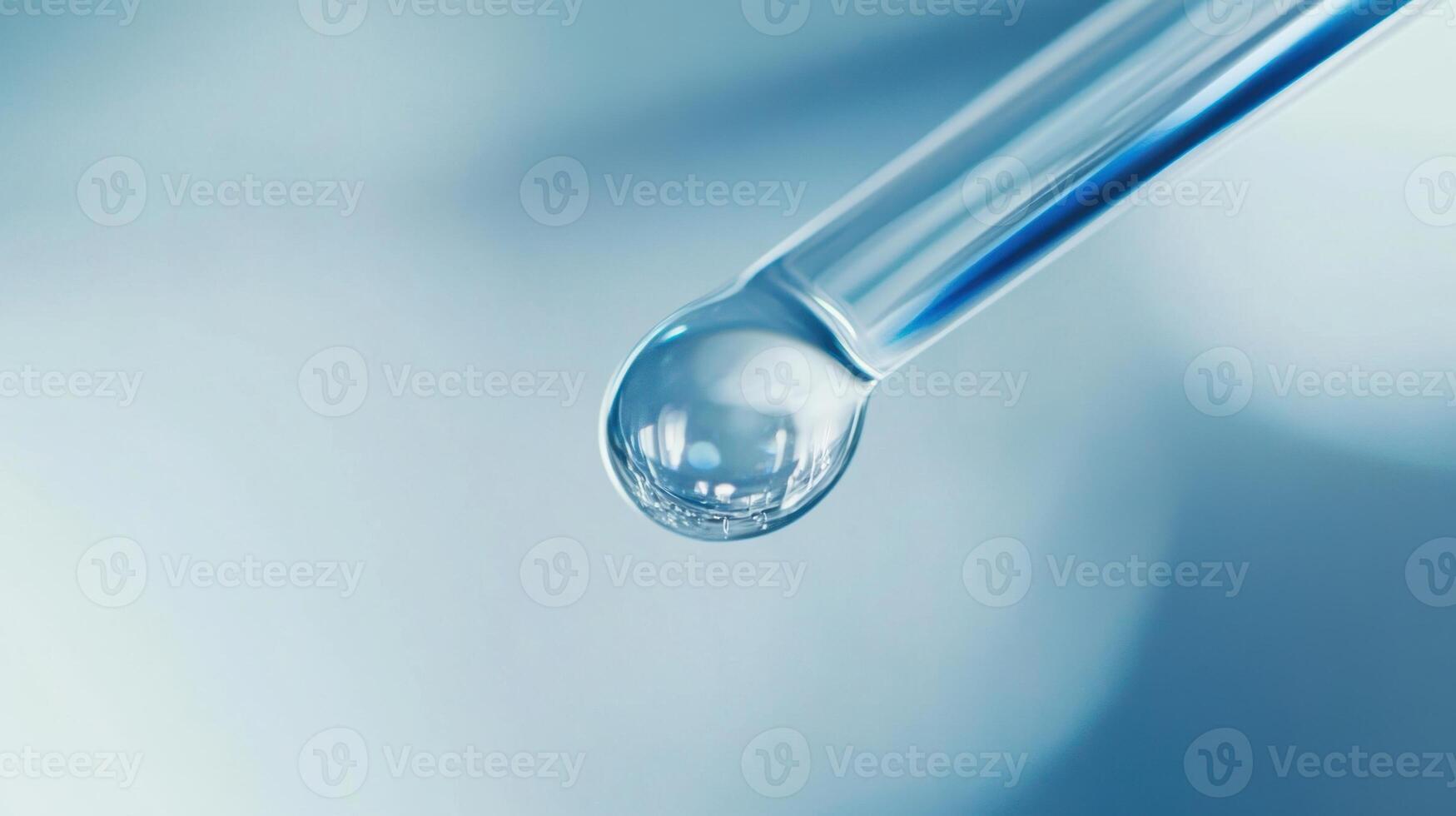Close-up of dropper with liquid droplet against blurred blue background photo