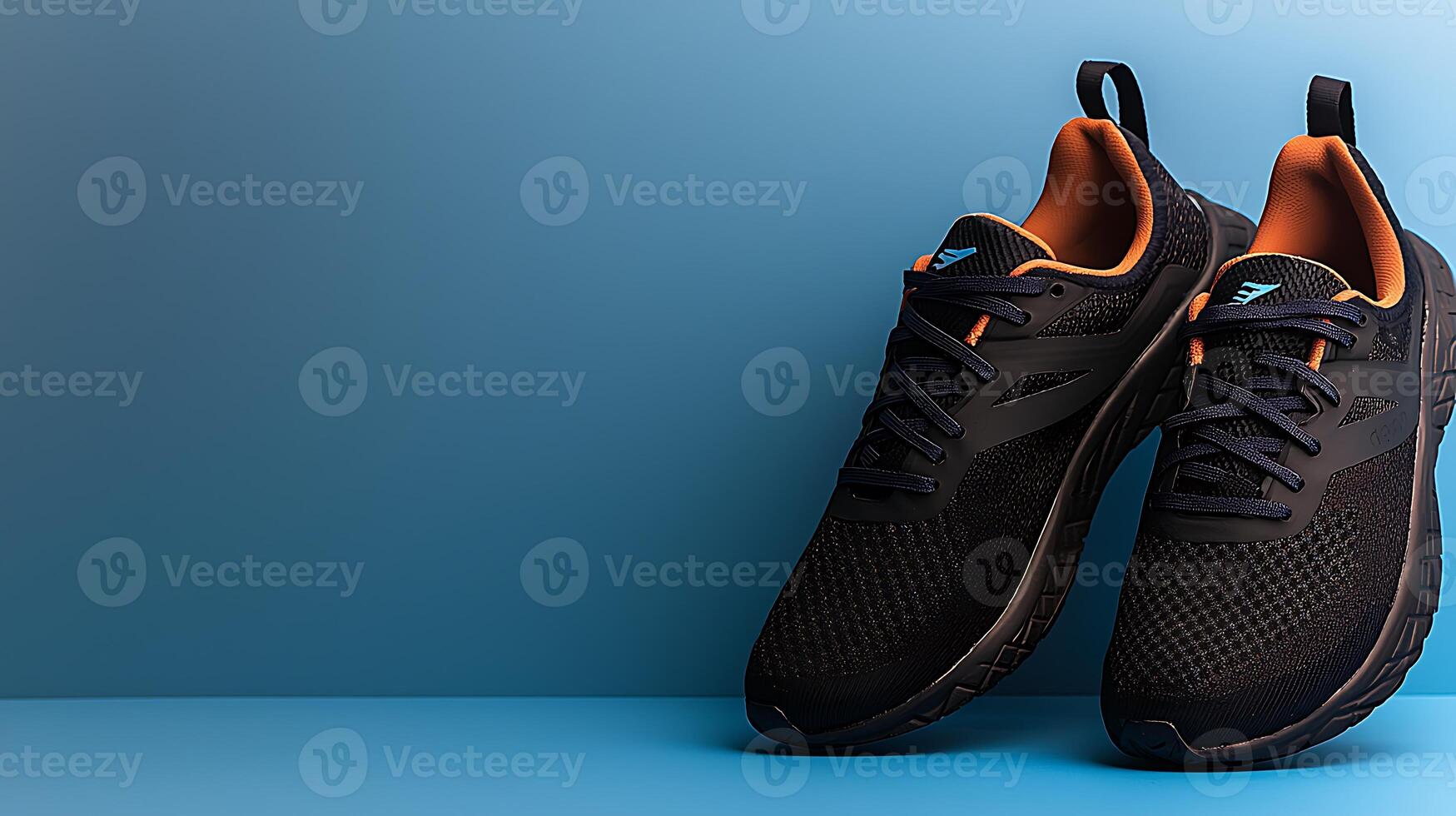 Stylish black running shoes with orange accents placed on a blue background, ideal for athletic promotions photo