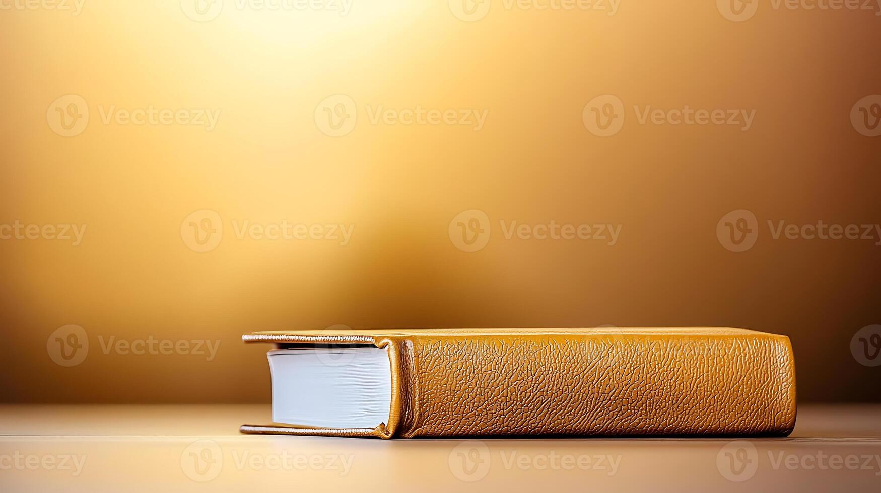 A close-up of a textured golden book resting on a smooth surface with a warm background glow photo