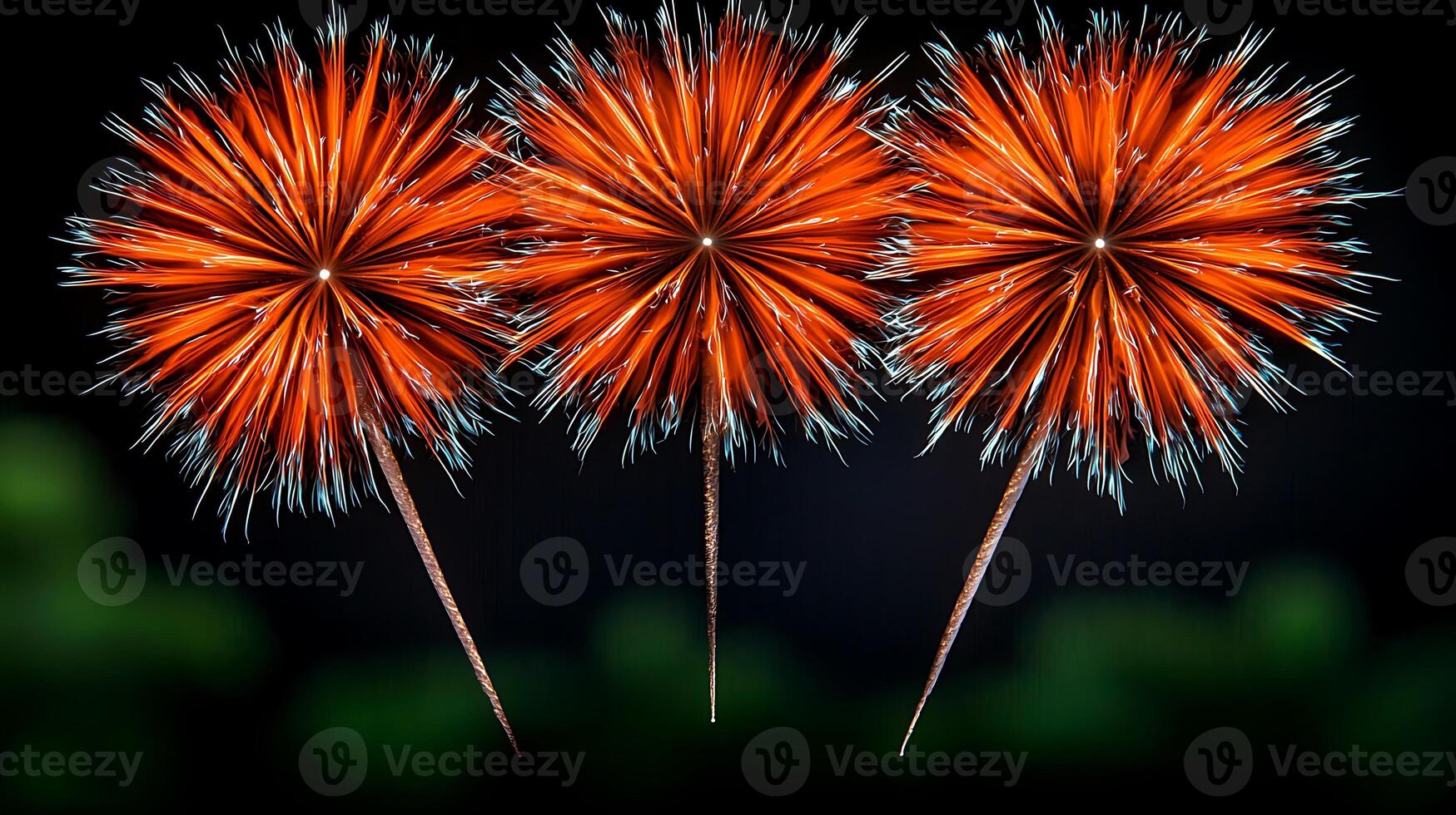 Three vibrant orange fireworks burst in the night sky, illuminating a dark background with greenery photo