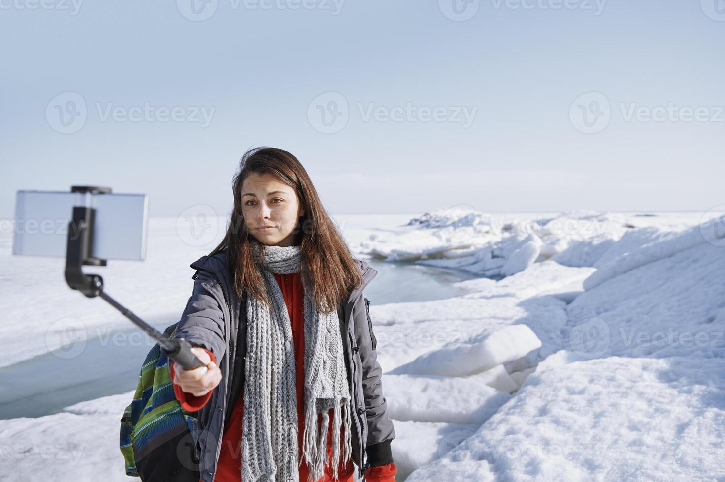 Female traveler at icy landscape using monopod photo