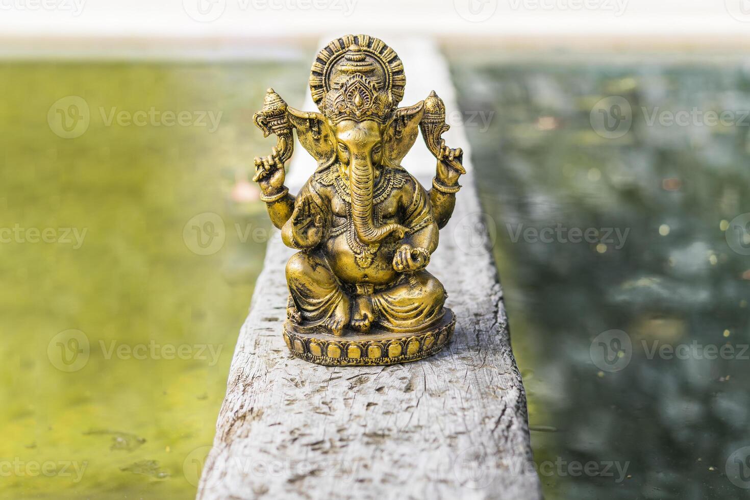 Gold Ganesha statue on a trunk over the water. Copy space photo