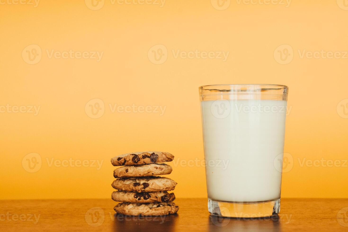 Delicious Cookies and Milk on a Wooden Table with an Orange Background. photo