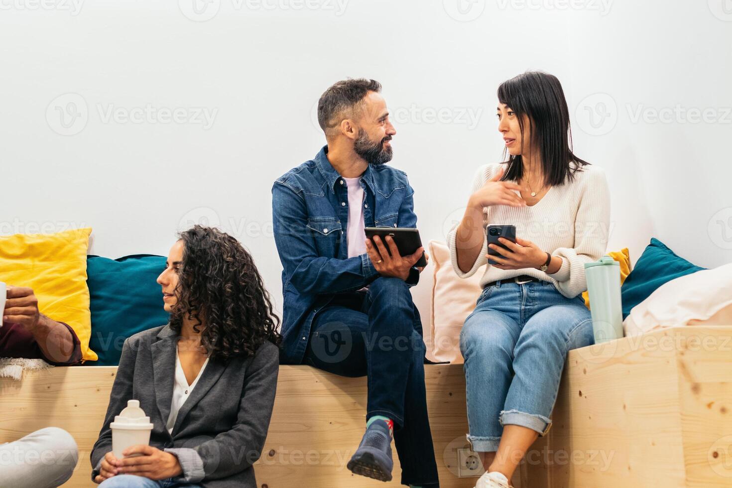 Coworkers in an informal meeting during a break. They discuss company data while having coffee in the break area of the modern coworking office photo