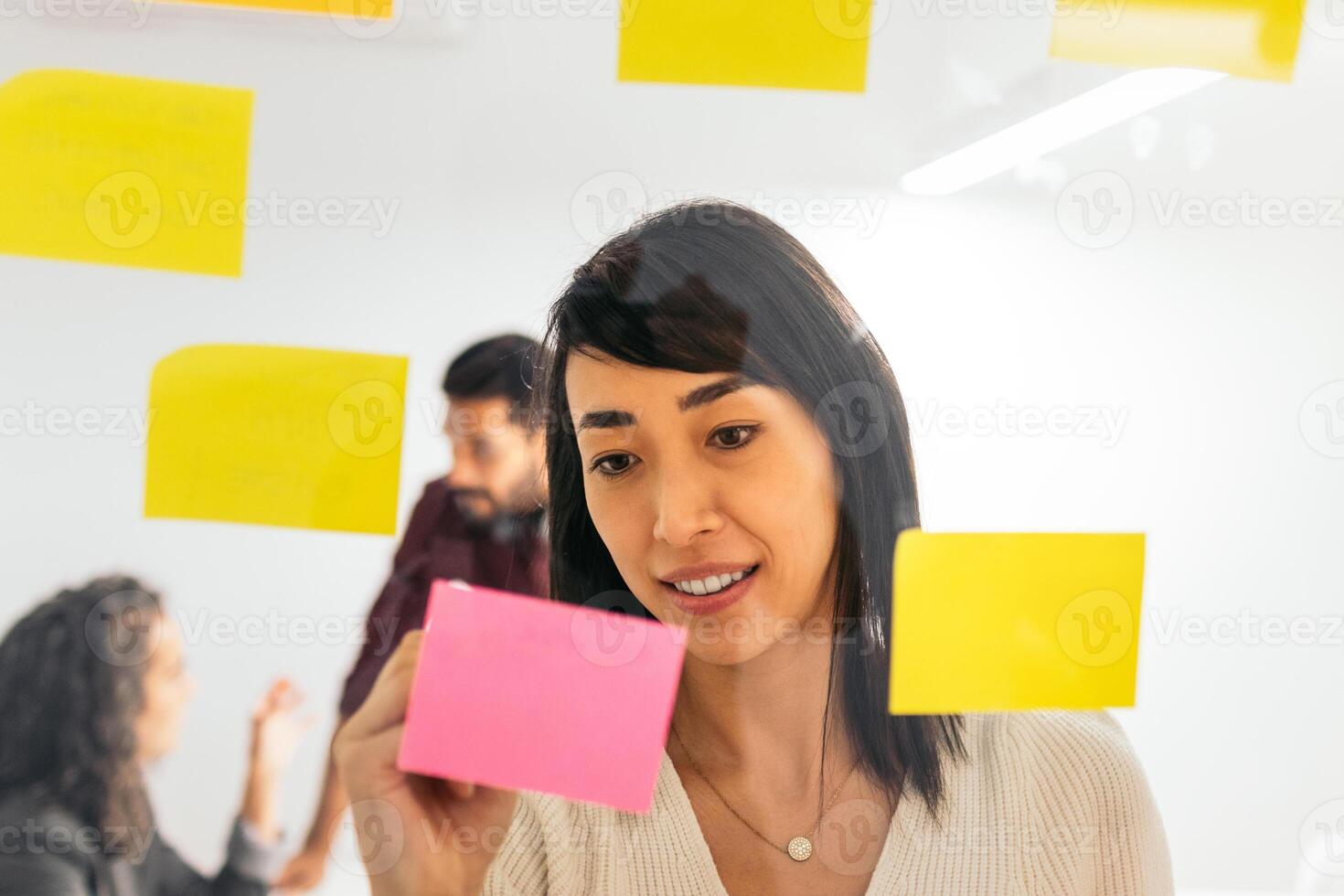 Asian woman writing on sticky notes brainstorming ideas from company meeting in coworking space photo