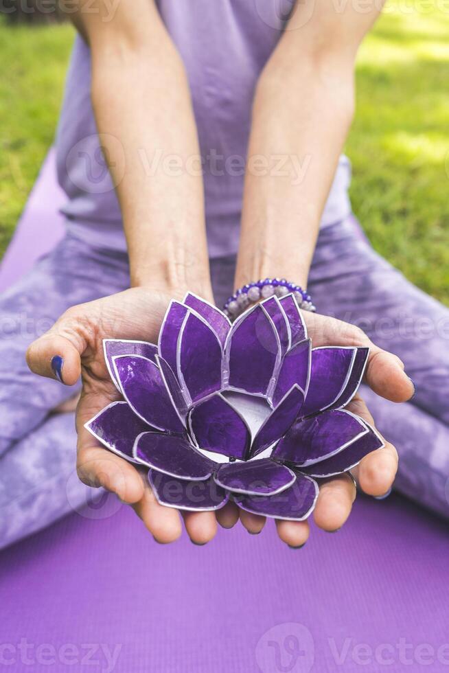 Close up of woman's hands offering a purple glass lotus. Yoga and meditation concept. photo