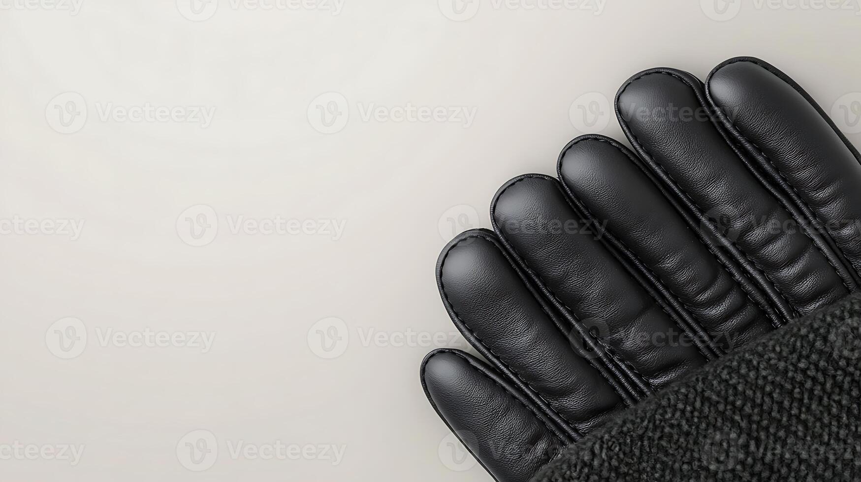 Close-up of black leather glove fingers resting on a smooth, light-colored surface photo