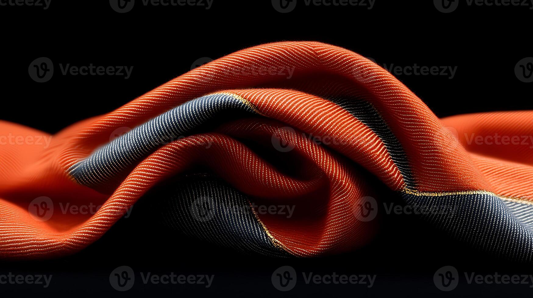Close-up of a folded vibrant orange and gray fabric showcasing intricate texture against a dark backdrop photo