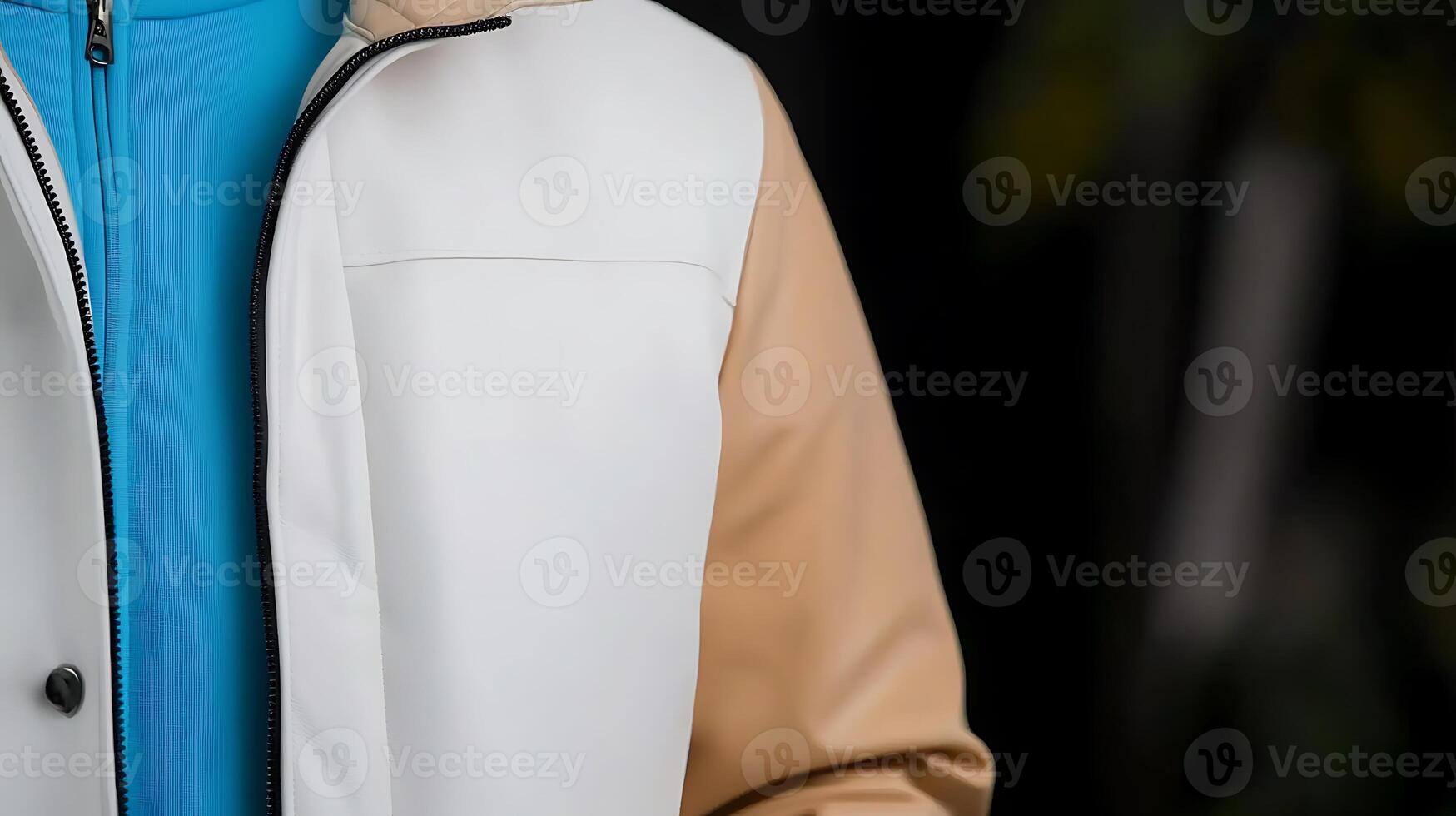Close-up of a person wearing a stylish jacket with contrasting colors against a blurred background photo