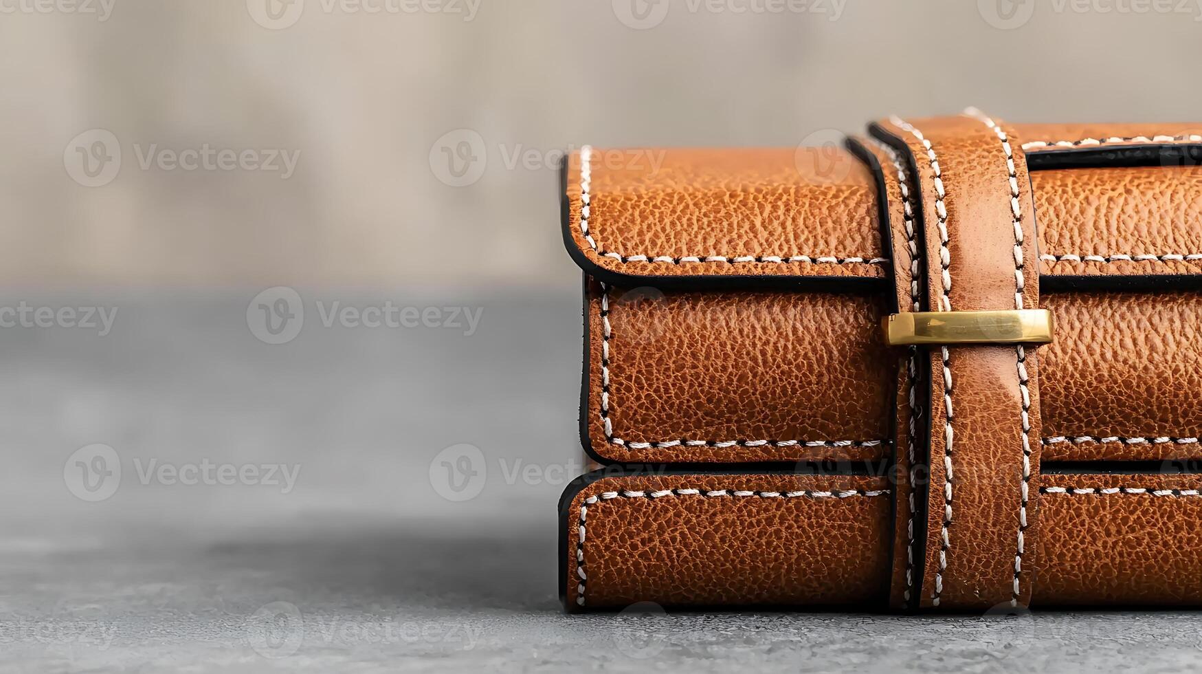 Close-up of a stylish brown leather wallet on a textured gray surface with a blurred background photo