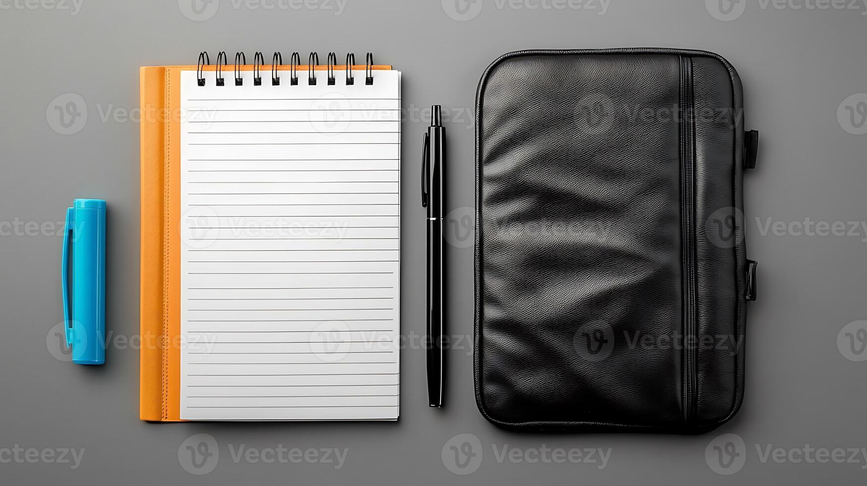 Stationery setup featuring a notepad, pen, highlighter, and a black case on a gray surface photo