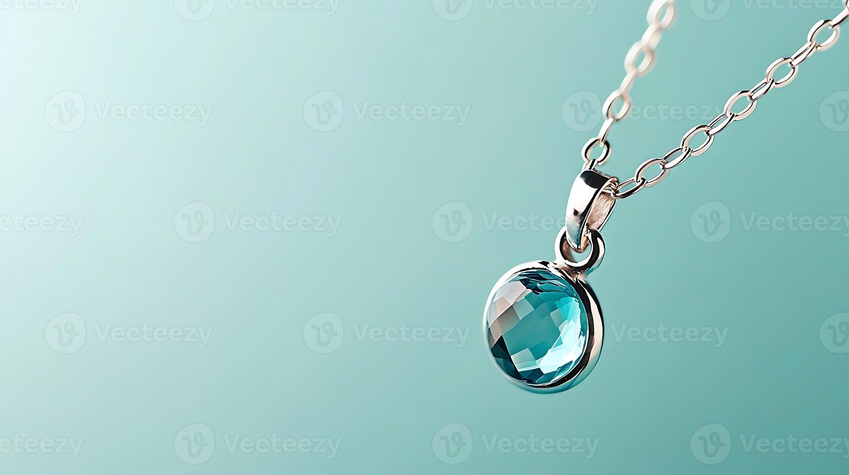 Close-up of a sparkling turquoise pendant hanging from a delicate silver chain against a soft gradient background photo
