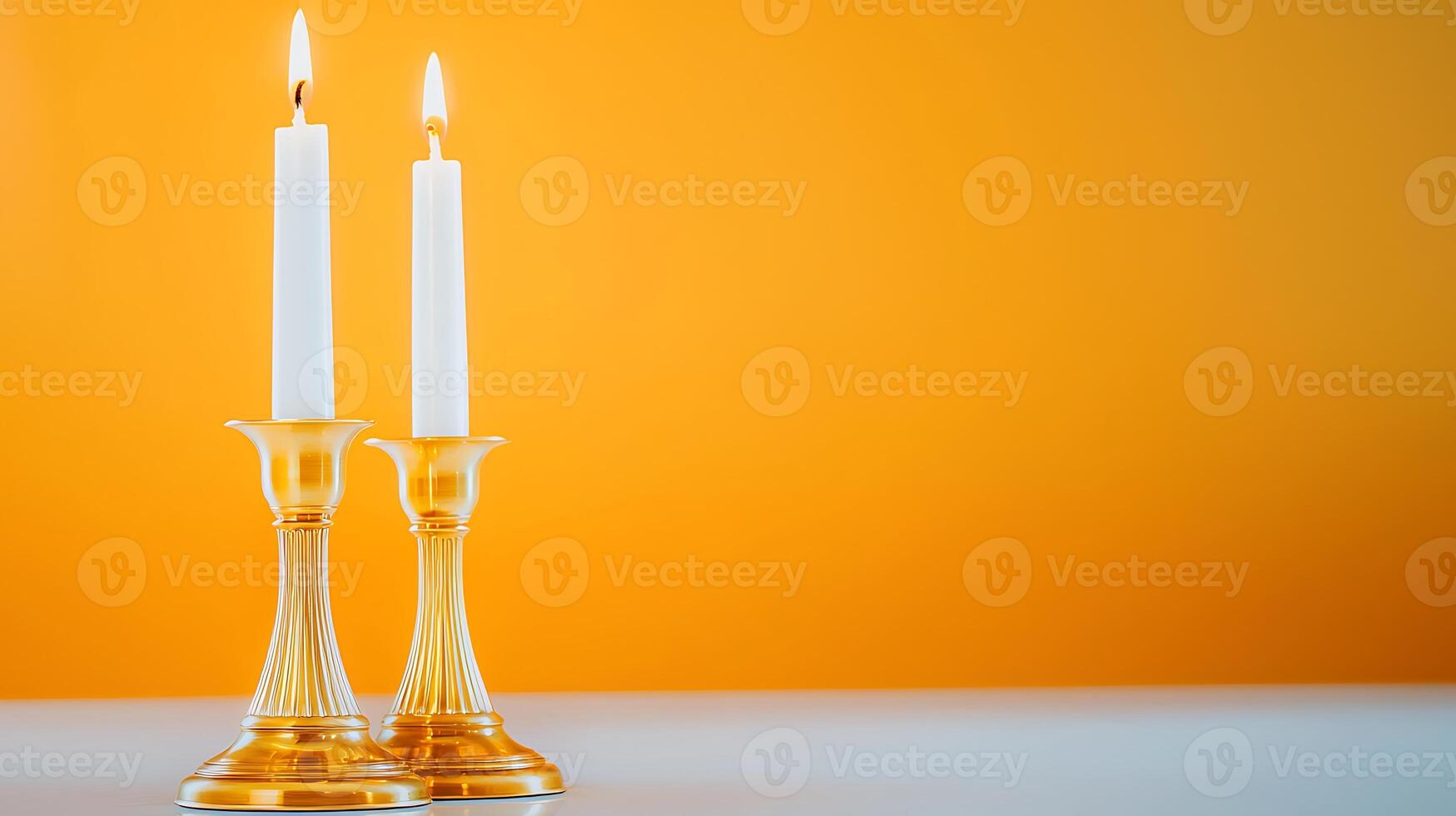 Two elegant candles in glass holders against a vibrant orange background, creating a warm ambiance photo