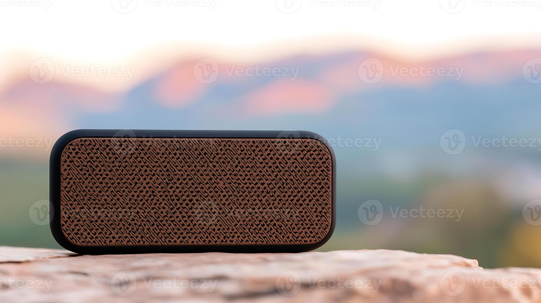 Portable speaker on a rock with blurred mountain landscape and sunset in the background photo