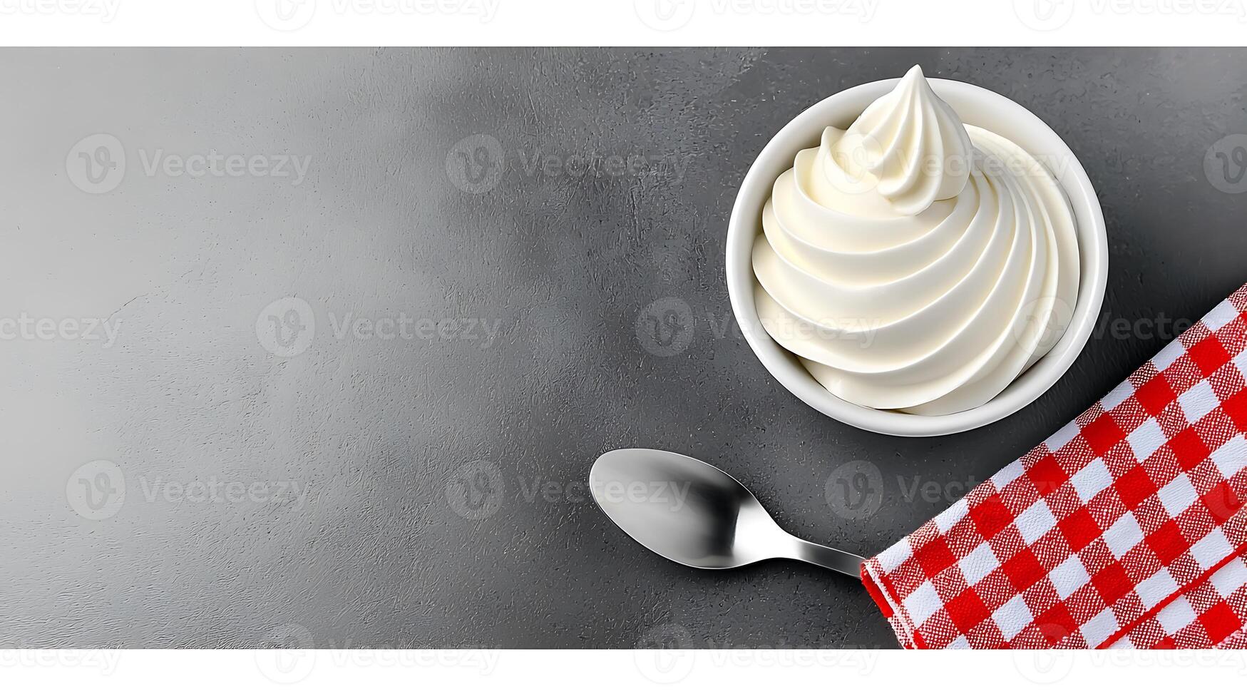 Creamy soft-serve ice cream in a bowl on a gray surface with a checkered napkin and spoon photo