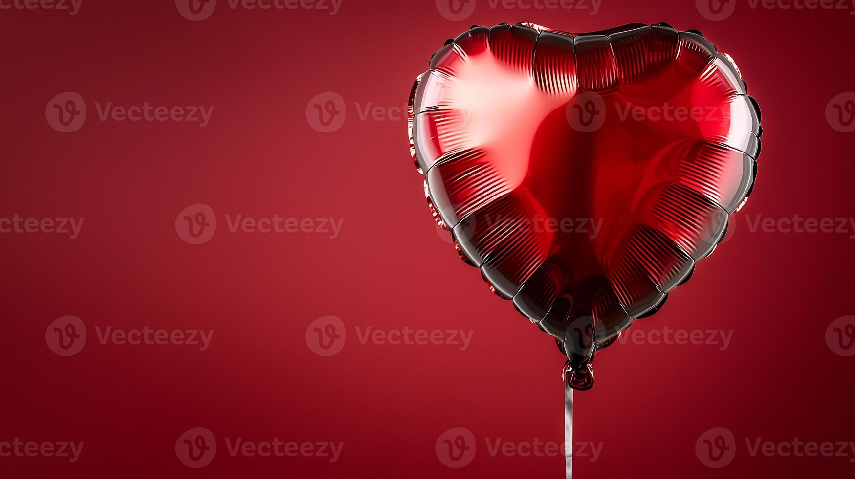 Shiny red heart-shaped balloon floating against a deep red background, evoking love and celebration photo