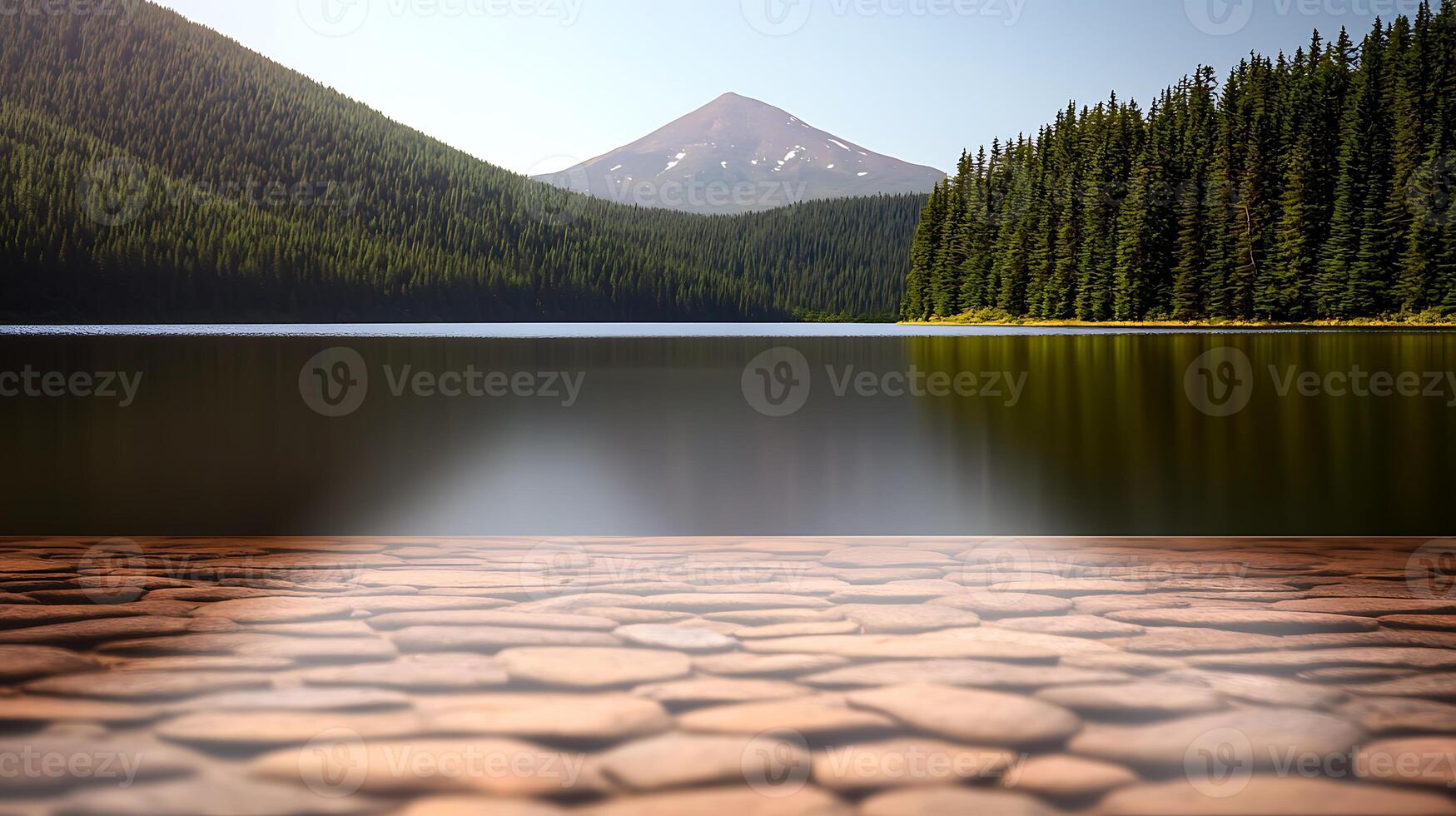Serene lake view with smooth pebbles in foreground, surrounded by lush forest and mountain backdrop photo