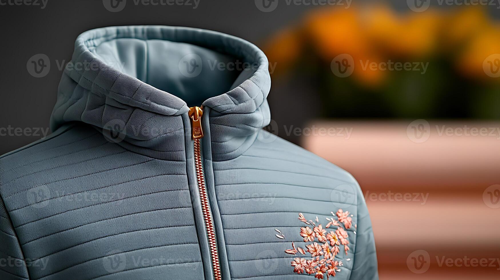 Close-up of a stylish blue zip-up jacket with floral embroidery against a blurred background photo