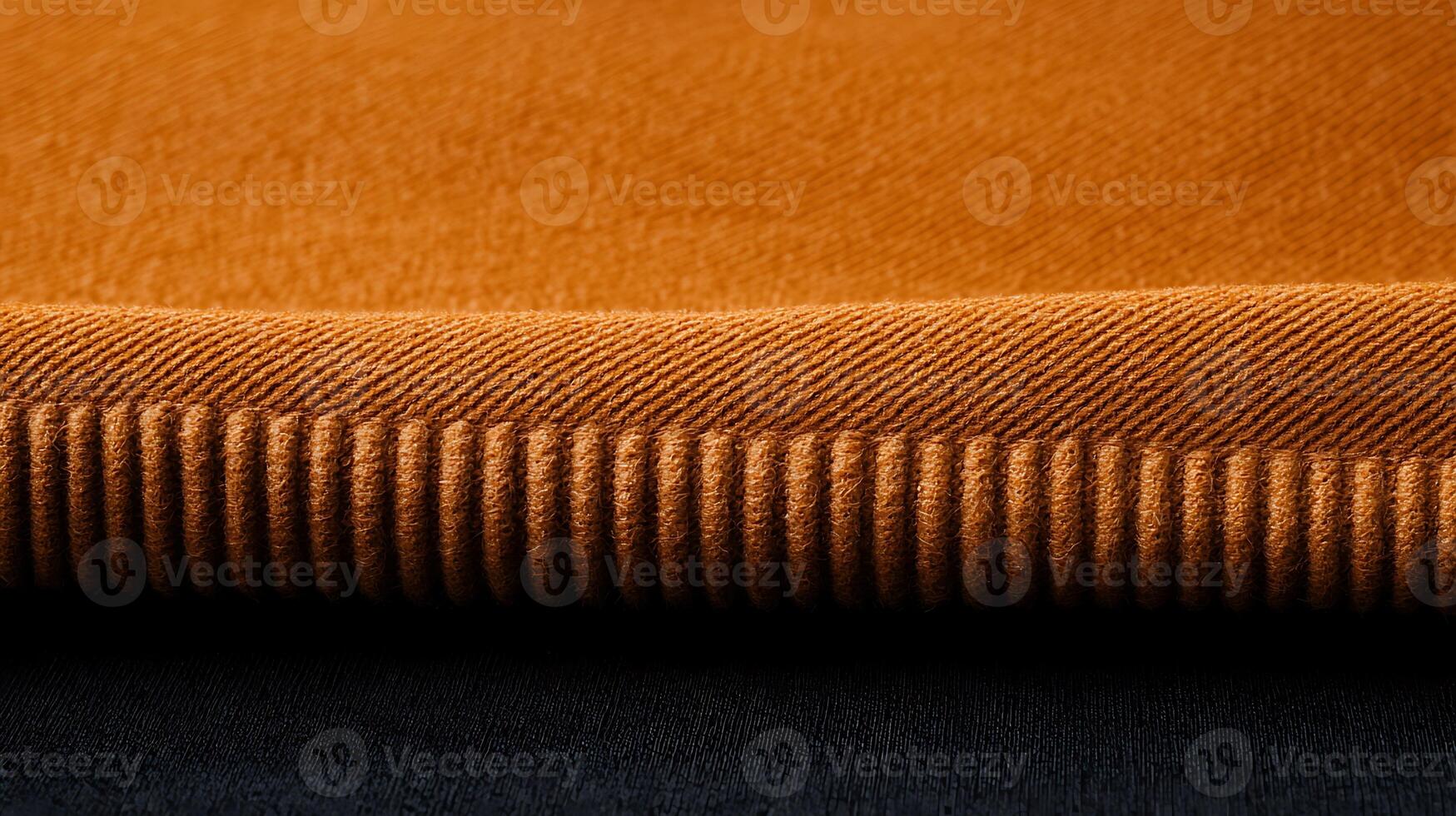 Close-up of textured orange fabric edge showcasing fine details against a dark background photo