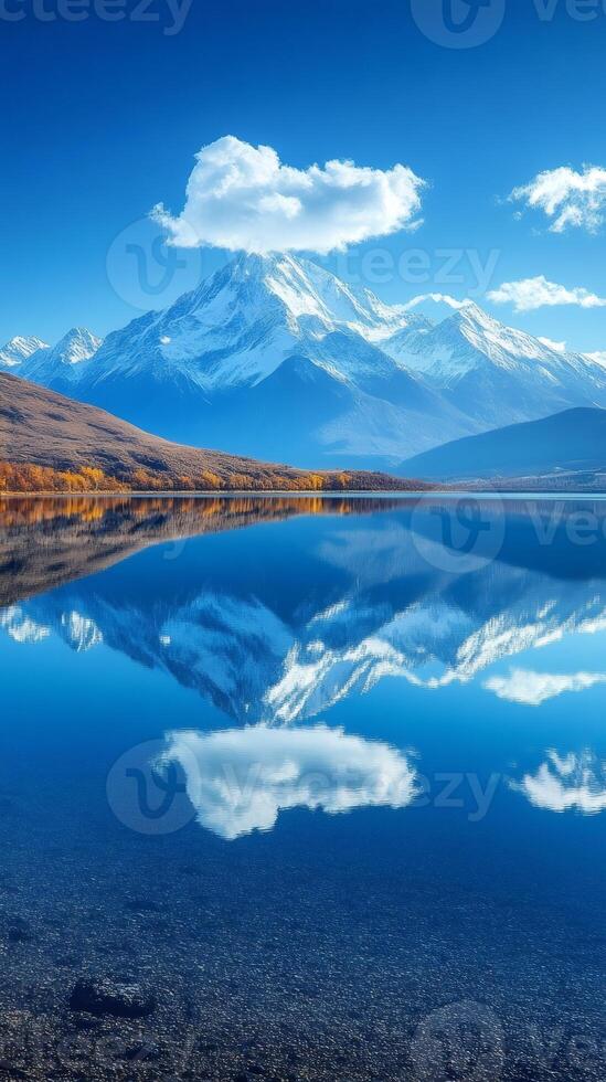 Snow capped mountains reflecting in a lake under a blue sky photo