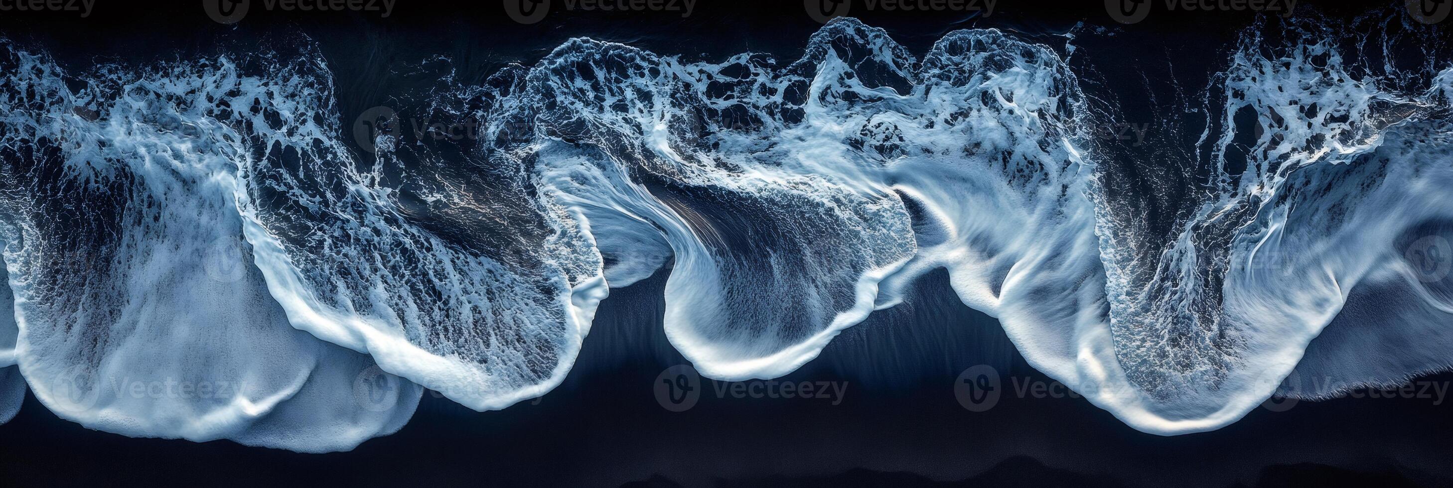 Aerial view of ocean waves crashing on black sand beach photo