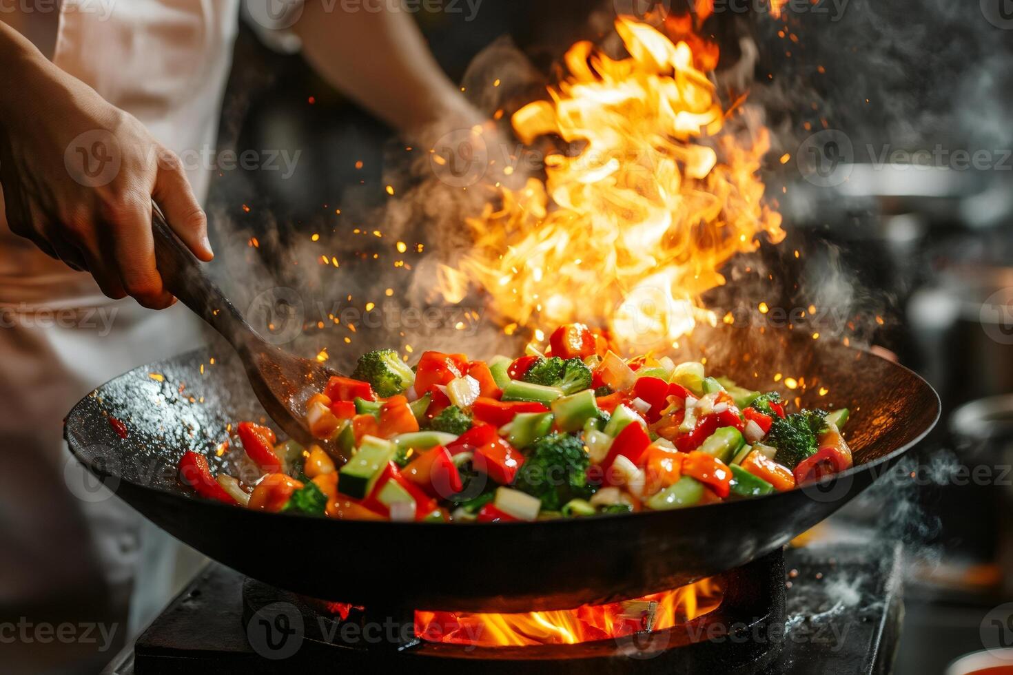 Chef cooking vegetables in wok with flames and steam photo