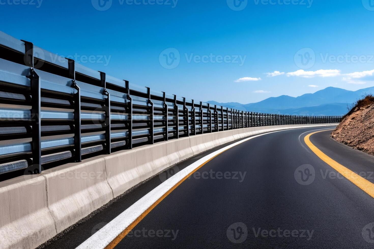 Highway winding through mountains with guardrail and clear blue sky photo