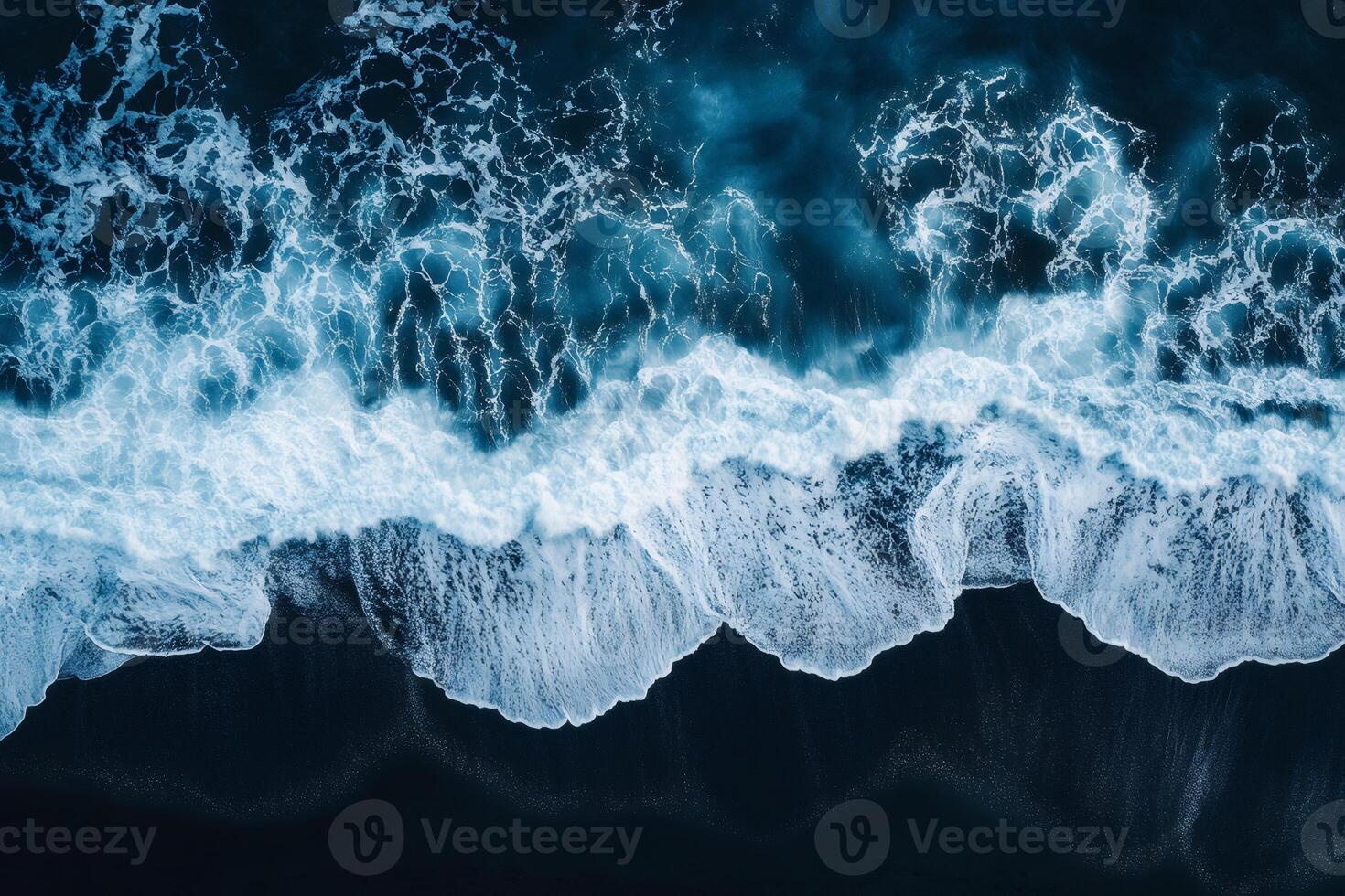 White ocean waves crashing on black sand beach, aerial view of powerful nature photo