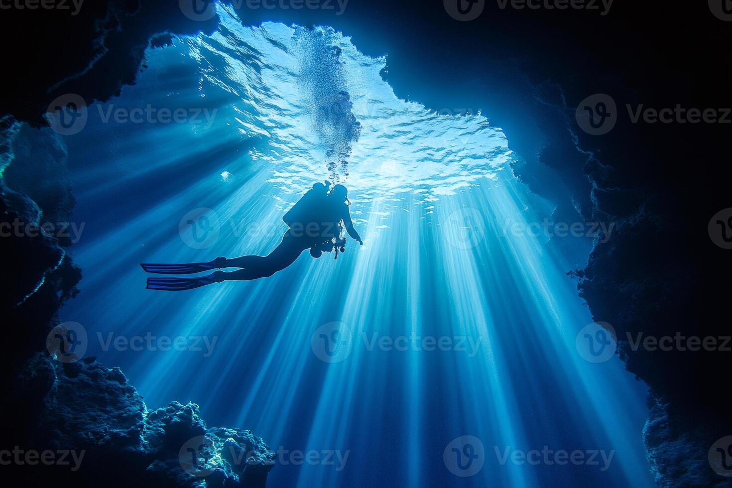 Scuba diver exploring underwater cave with sunbeams penetrating through surface photo