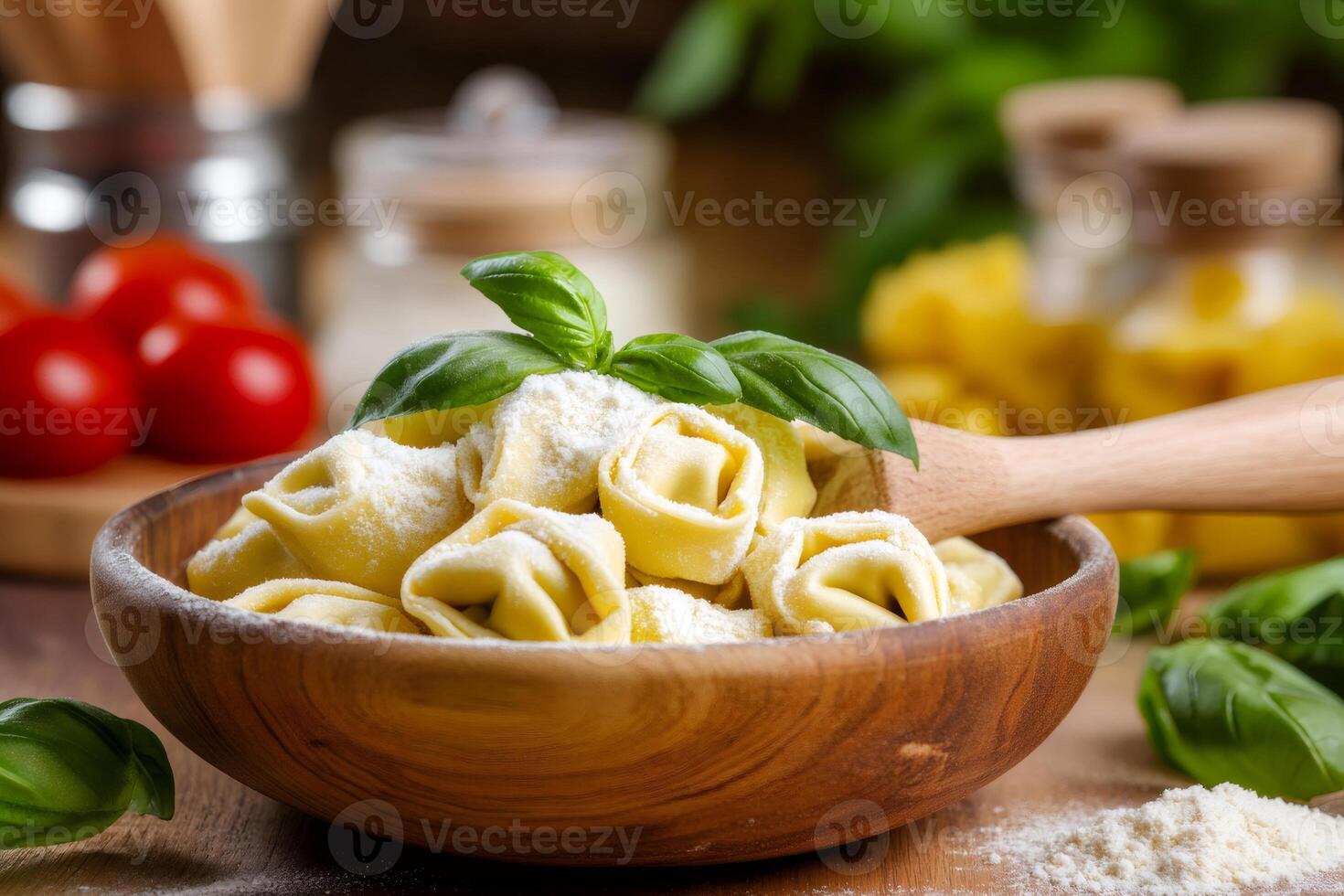 Fresh tortellini with basil and flour in wooden bowl on kitchen table photo