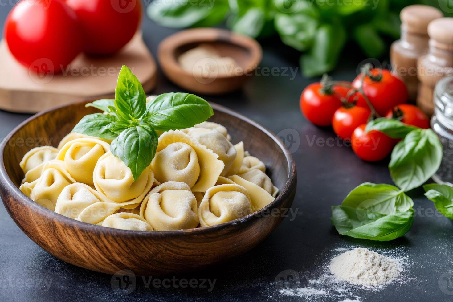 Delicious uncooked tortellini with basil in wooden bowl on dark background photo