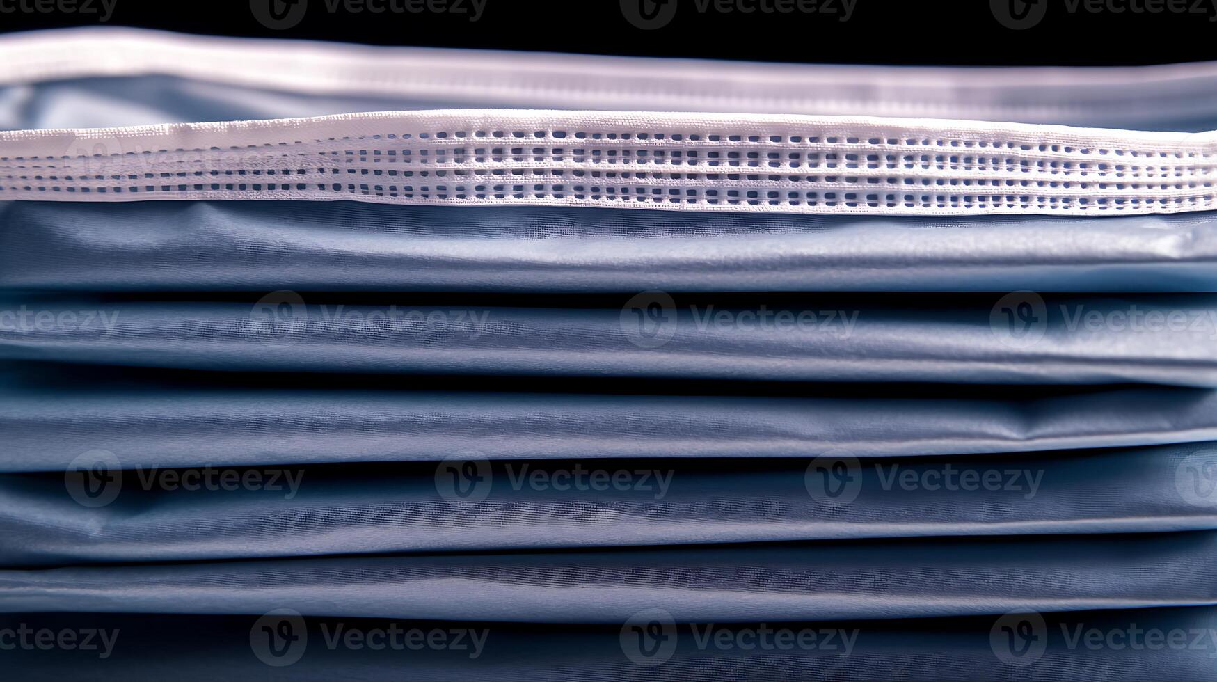 Close-up view of stacked blue surgical masks highlighting texture and folds, set against a dark background photo
